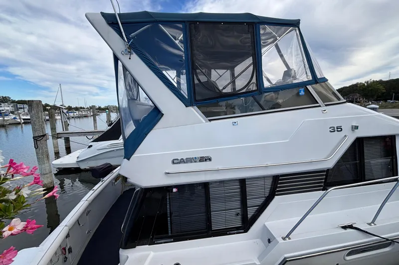 Slide: The Image of 1993 Carver 350 Voyager yacht docked at marina, featuring blue canopy and sleek design. - 35