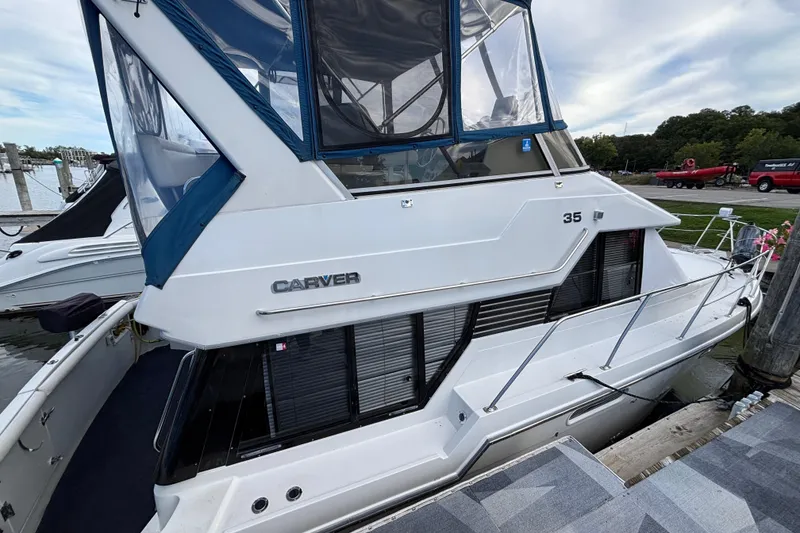 Slide: The Image of 1993 Carver 350 Voyager yacht docked at marina, featuring sleek design and blue canopy. - 34
