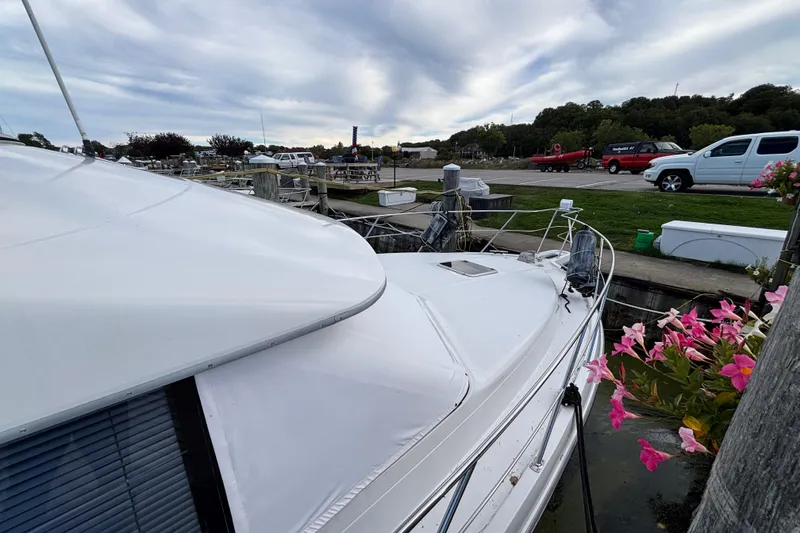 Slide: The Image of 1993 Carver 350 Voyager docked, surrounded by flowers and parked vehicles under a cloudy sky. - 36