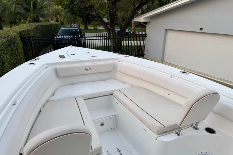 Slide: The Image of 2021 Sea Hunt Gamefish 25 boat with white cushioned seating in a driveway setting. - 12