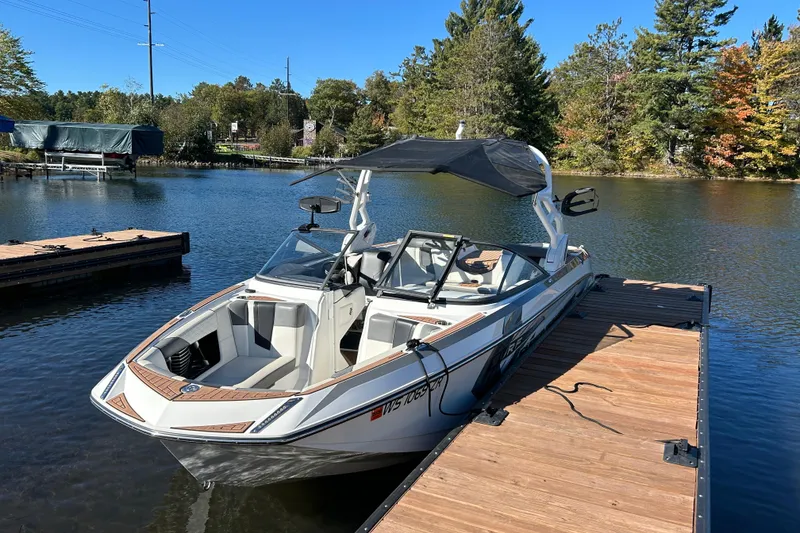 Slide: The Image of 2017 Nautique Super Air Nautique G23 boat docked on a serene lake. - 2