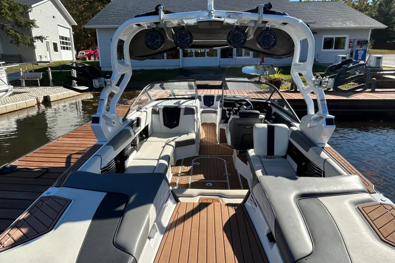 Slide: The Image of 2017 Nautique Super Air Nautique G23 boat interior with seating and speakers at a dock. - 5