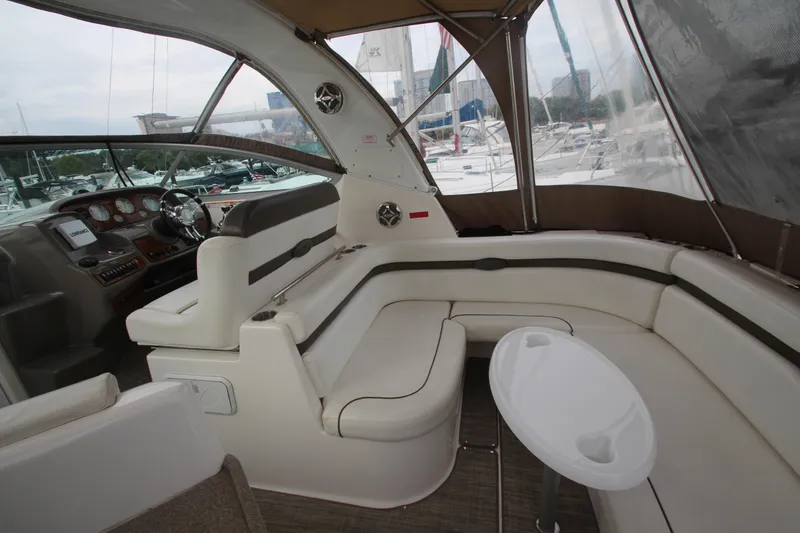 Slide: The Image of 2008 Rinker 330 Express Cruiser interior with plush seating and helm, docked at marina. - 10