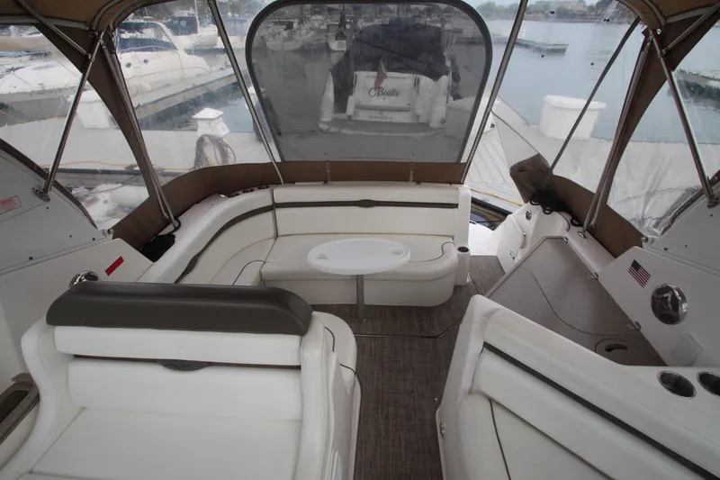 Slide: The Image of 2008 Rinker 330 Express Cruiser interior with seating and table, docked at marina. - 13