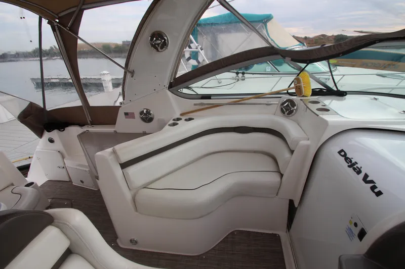 Slide: The Image of 2008 Rinker 330 Express Cruiser interior with white seating and dashboard, docked by the water. - 17