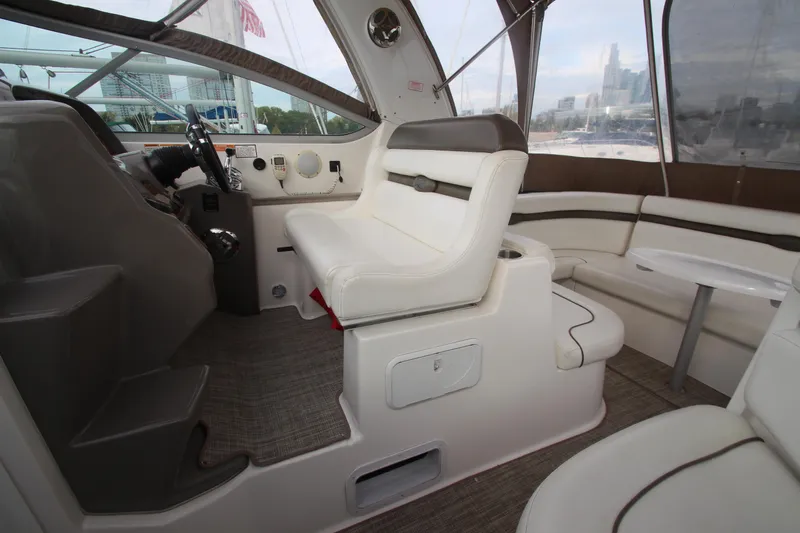 Slide: The Image of 2008 Rinker 330 Express Cruiser interior with helm, seating, and table in a marina setting. - 20