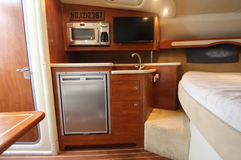 Slide: The Image of 2008 Rinker 330 Express Cruiser interior with kitchenette, microwave, TV, and bed. - 26