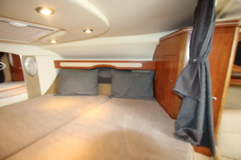 Slide: The Image of 2008 Rinker 330 Express Cruiser cabin interior with cozy bedding and wooden cabinetry. - 35