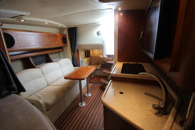 Slide: The Image of 2008 Rinker 330 Express Cruiser interior with kitchenette, seating, and wooden accents. - 37