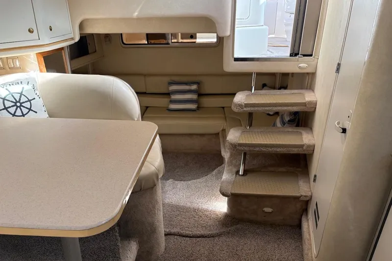 Slide: The Image of Interior of 2000 Sea Ray 310 Sundancer with cozy seating and carpeted stairs. - 12