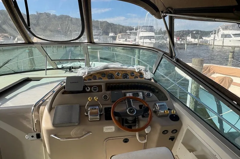 Slide: The Image of Cockpit view of 2000 Sea Ray 310 Sundancer at marina, featuring steering wheel and controls. - 5