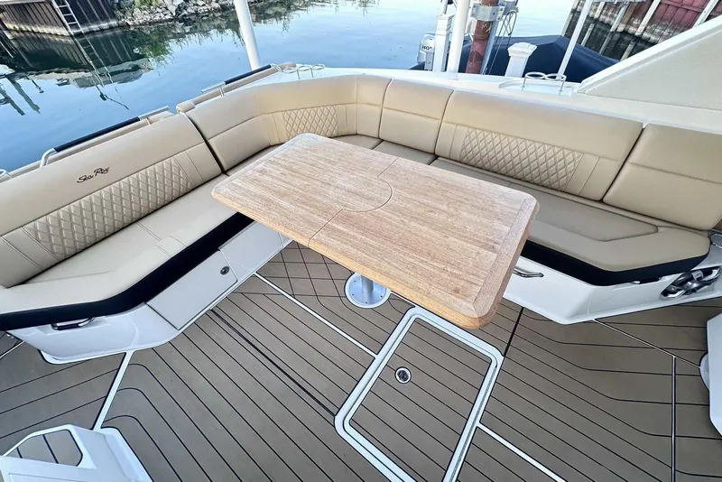 Slide: The Image of 2024 Sea Ray SLX 400 boat interior with beige seating and wooden table. - 14