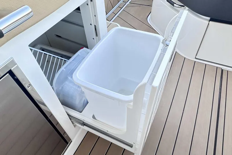 Slide: The Image of 2024 Sea Ray SLX 400 boat interior with open storage compartment and ice bucket. - 21