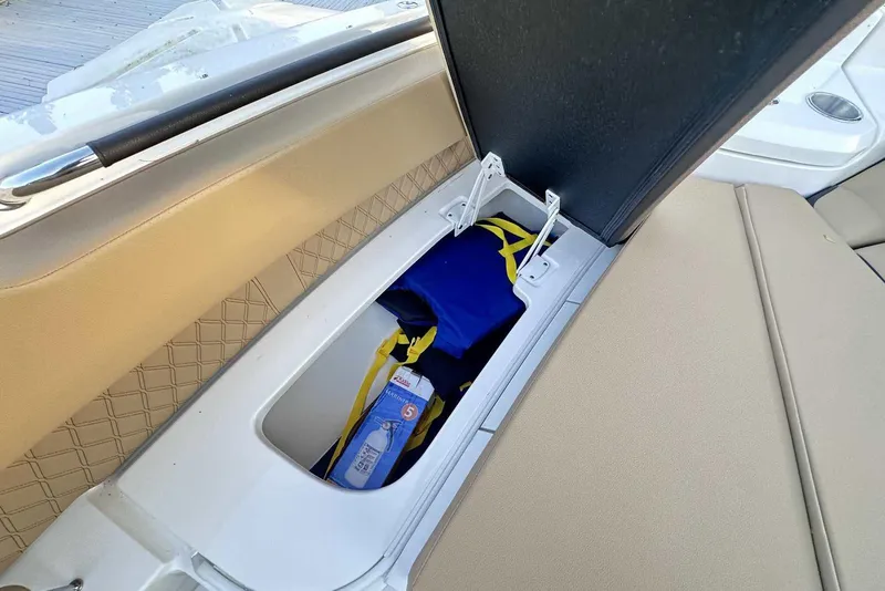 Slide: The Image of 2024 Sea Ray SLX 400 boat storage compartment with life jacket and fire extinguisher. - 37