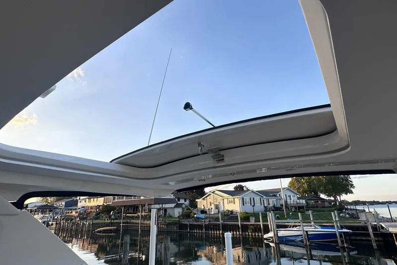 Slide: The Image of 2024 Sea Ray SLX 400 boat with open sunroof, docked near waterfront homes. - 41