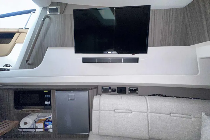 Slide: The Image of 2024 Sea Ray SLX 400 interior with TV, soundbar, microwave, and mini fridge. - 44