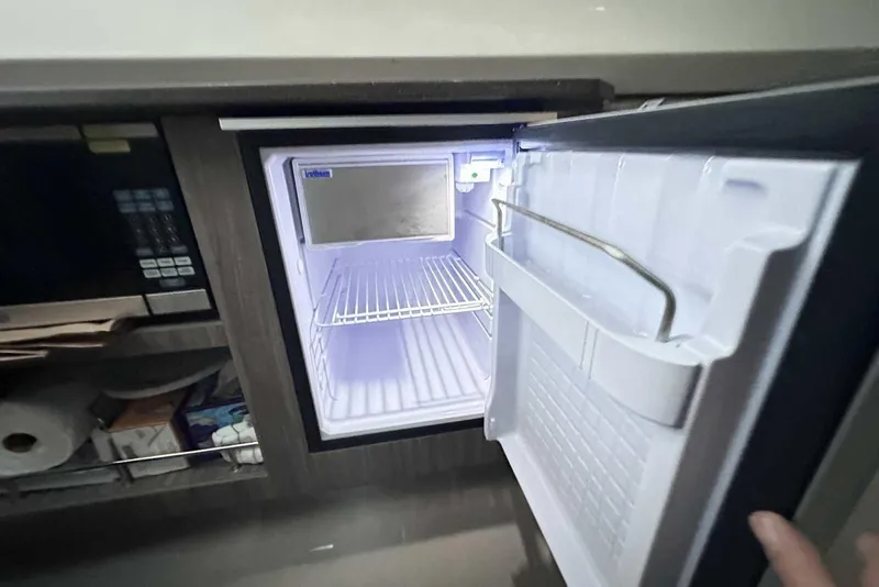 Slide: The Image of Open refrigerator inside 2024 Sea Ray SLX 400 boat, showcasing interior storage space. - 45
