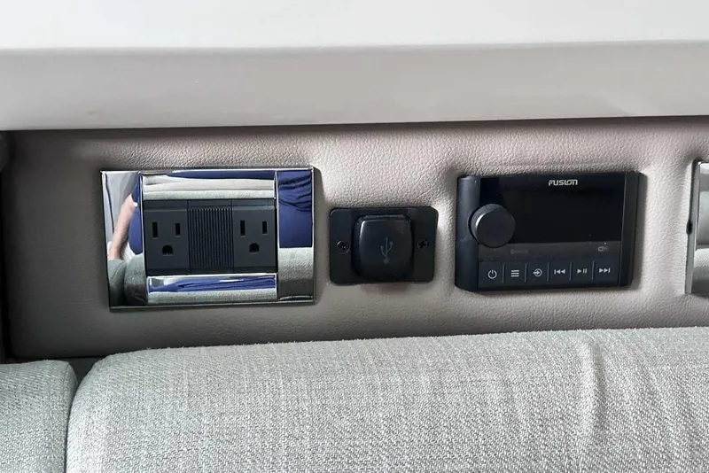 Slide: The Image of 2024 Sea Ray SLX 400 interior features power outlets and a Fusion audio control panel. - 46