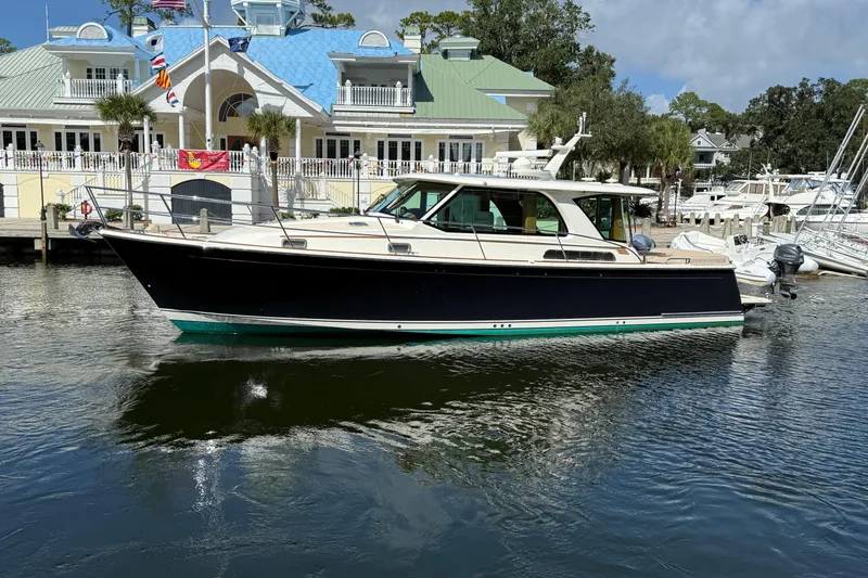 The Image of 2023 Sabre 43 Salon Express yacht docked at a marina with elegant architecture. - 0