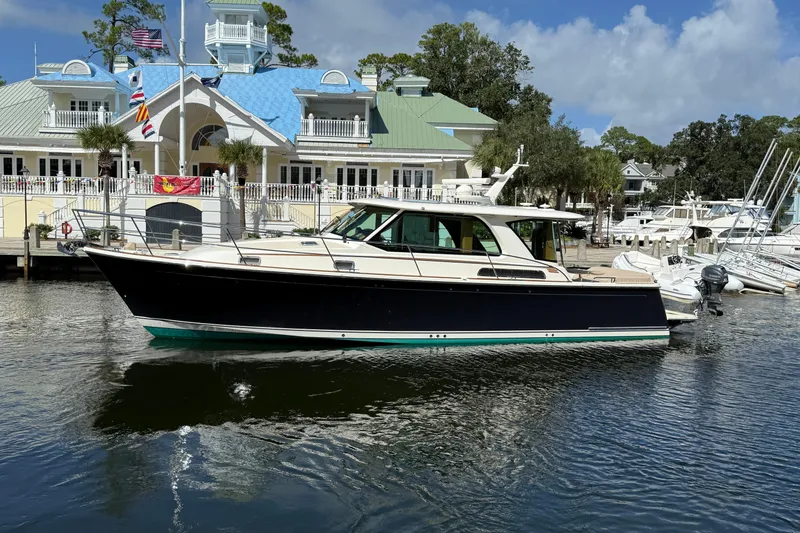 Slide: The Image of 2023 Sabre 43 Salon Express yacht docked at a marina with a scenic backdrop. - 1
