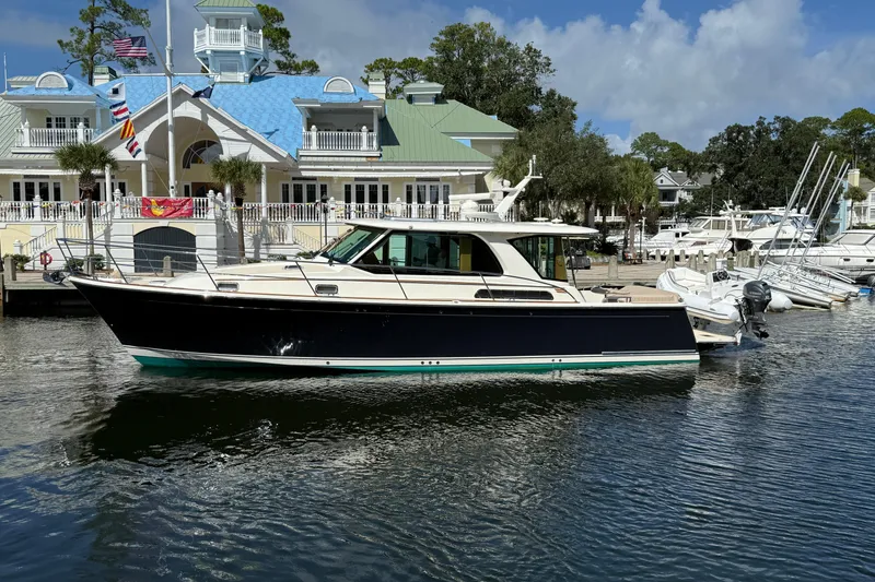 Slide: The Image of 2023 Sabre 43 Salon Express yacht docked at a marina with a scenic backdrop. - 2