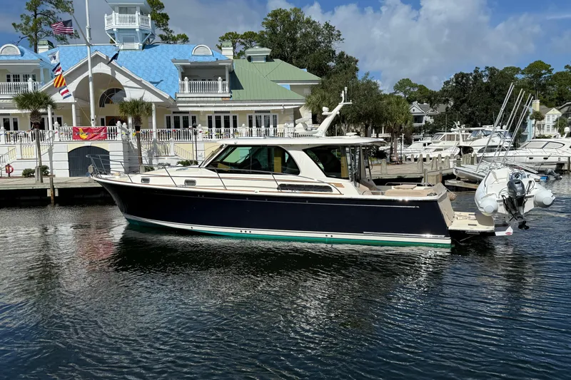 Slide: The Image of 2023 Sabre 43 Salon Express yacht docked at a marina with a scenic backdrop. - 3