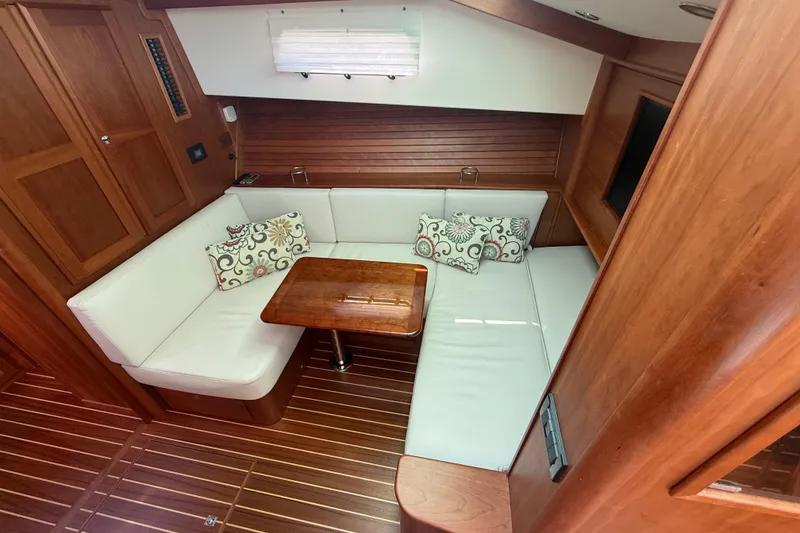 Slide: The Image of 2023 Sabre 43 Salon Express interior with wooden finish, white seating, and decorative pillows. - 65