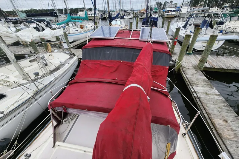 Slide: The Image of 1982 Pearson 323 sailboat with red cover and solar panels docked at marina. - 10