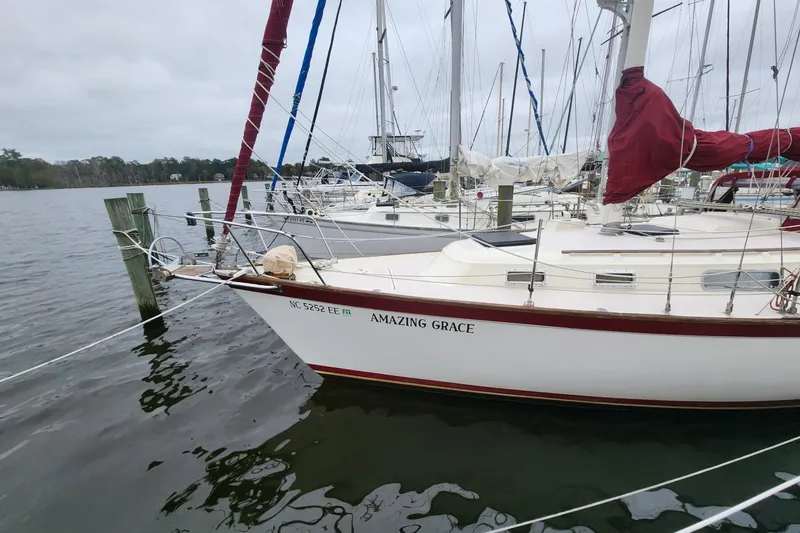 Slide: The Image of 1982 Pearson 323 sailboat docked, featuring maroon canvas and "Amazing Grace" on the stern. - 4