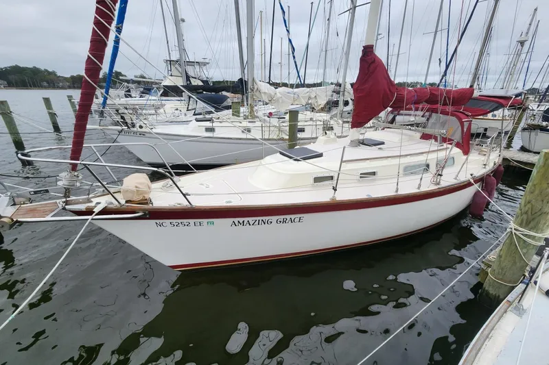 The Image of 1982 Pearson 323 sailboat "Amazing Grace" docked at marina with red sails. - 0