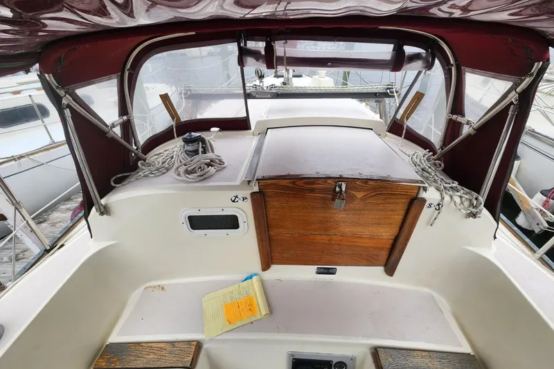 Slide: The Image of 1982 Pearson 323 sailboat cockpit with wooden hatch, ropes, and maroon canopy. - 12