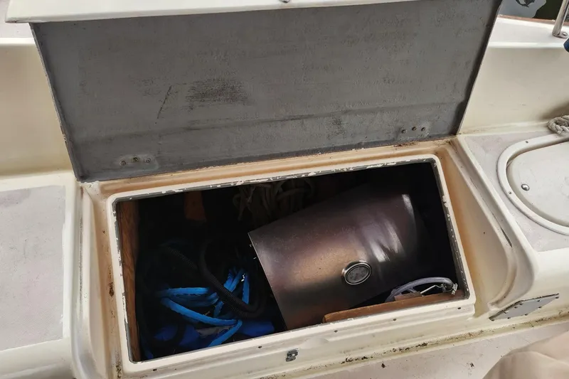 Slide: The Image of Open storage compartment on 1982 Pearson 323 sailboat, containing ropes and a metal cylinder. - 22
