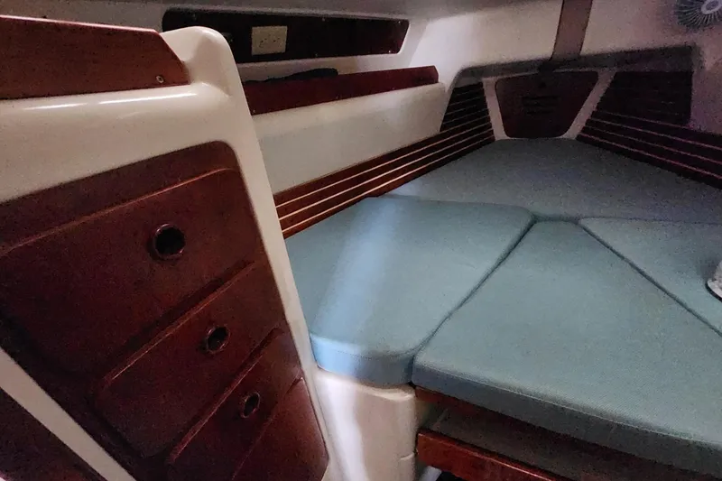 Slide: The Image of Interior of a 1982 Pearson 323 sailboat with wooden cabinets and blue cushions. - 41
