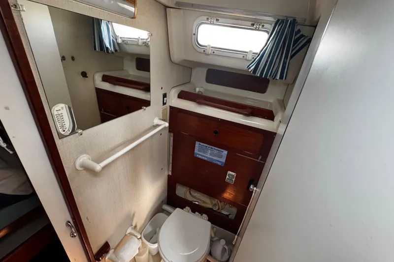 Slide: The Image of Compact bathroom in 1982 Pearson 323 sailboat with mirror, toilet, and wooden cabinetry. Jabsco toilet - 48