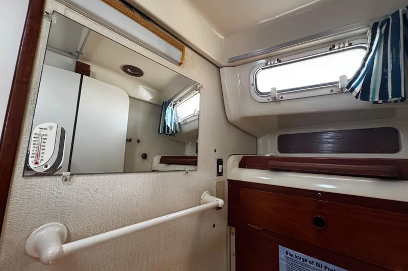 Slide: The Image of head area starboard side, interior with mirror, window, and wooden cabinetry. - 49
