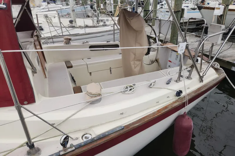 Slide: The Image of 1982 Pearson 323 sailboat docked, featuring a spacious cockpit and maroon accents. - 5