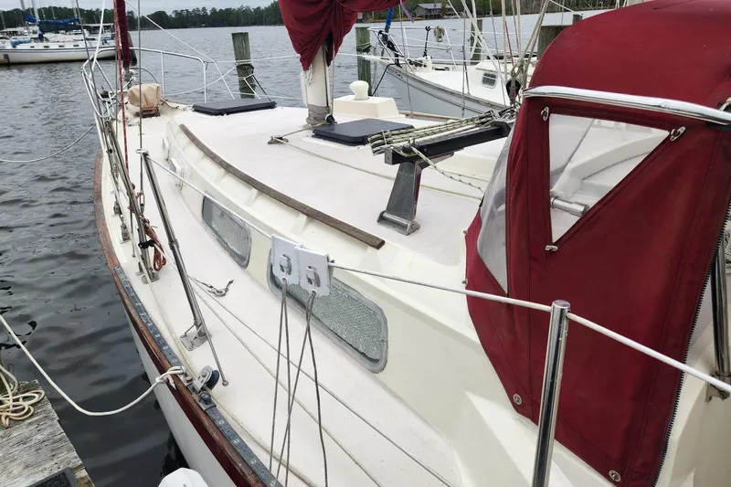 Slide: The Image of 1982 Pearson 323 sailboat with maroon canvas, docked in a marina. - 6