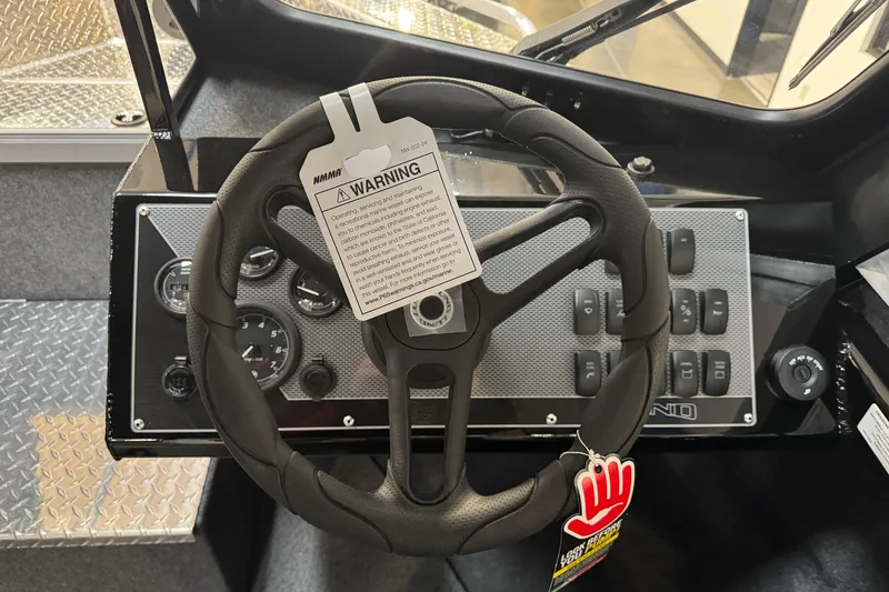 Slide: The Image of Steering wheel of 2026 Lund 200 Heavy Gauge boat with warning tag and control panel. - 35