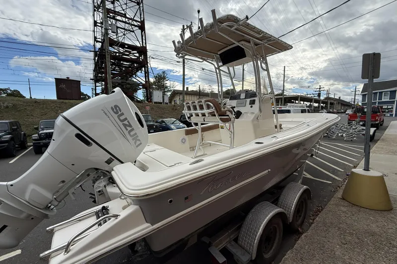 Slide: The Image of 2023 Pioneer 220 Bay Sport boat with Suzuki engine on trailer in parking lot. - 2