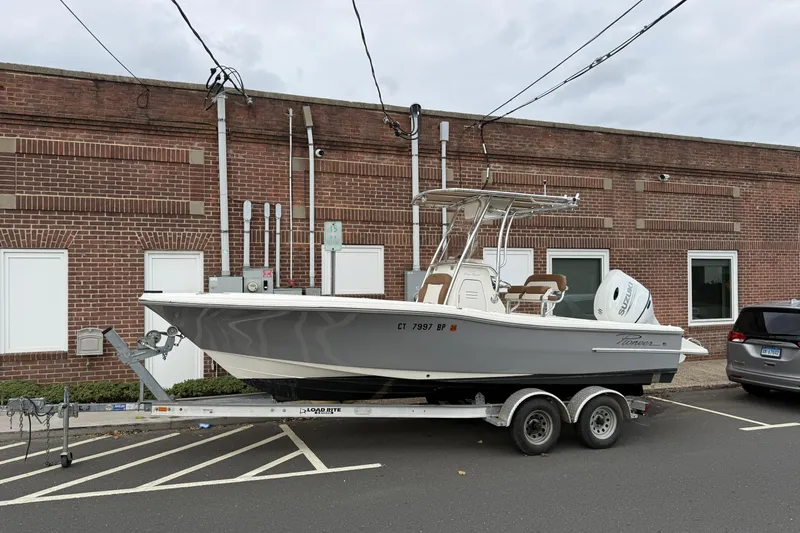 Slide: The Image of 2023 Pioneer 220 Bay Sport boat on trailer, parked by a brick building. - 25