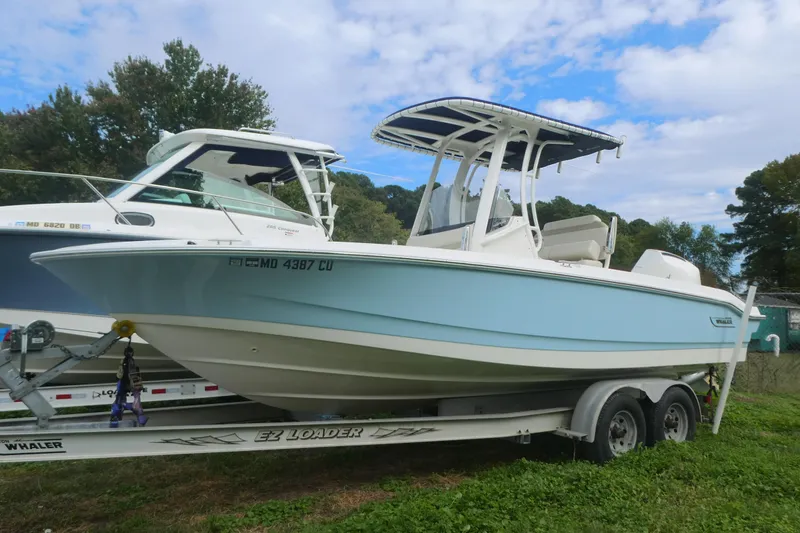 The Image of 2024 Boston Whaler 220 Dauntless boat on trailer, parked outdoors under blue sky. - 0
