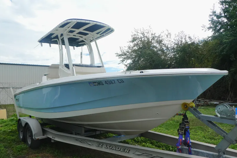 Slide: The Image of 2024 Boston Whaler 220 Dauntless boat on trailer, light blue hull, outdoor setting. - 14