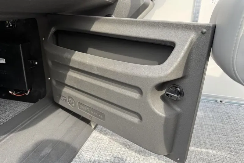 Slide: The Image of 2026 Sun Tracker Party Barge 18 DLX storage compartment with latch, gray interior. - 15