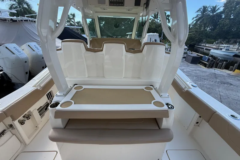 Slide: The Image of 2022 Scout 355 LXF boat interior with seating and cup holders, docked near palm trees. - 10