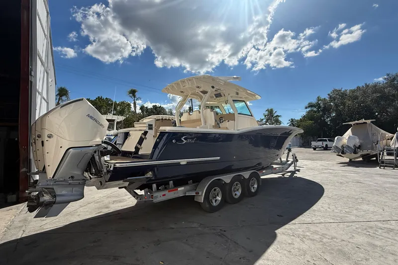 Slide: The Image of 2022 Scout 355 LXF boat on trailer under sunny sky with clouds. - 2