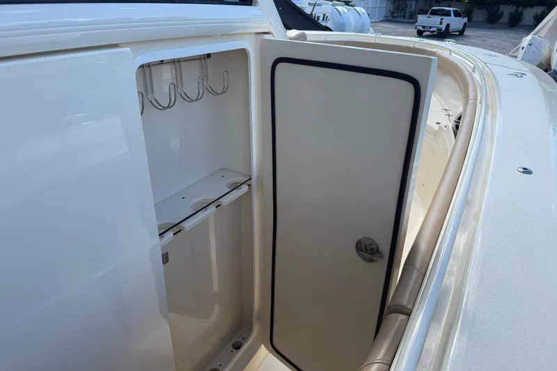 Slide: The Image of 2022 Scout 355 LXF boat storage compartment with hooks and door open. - 23