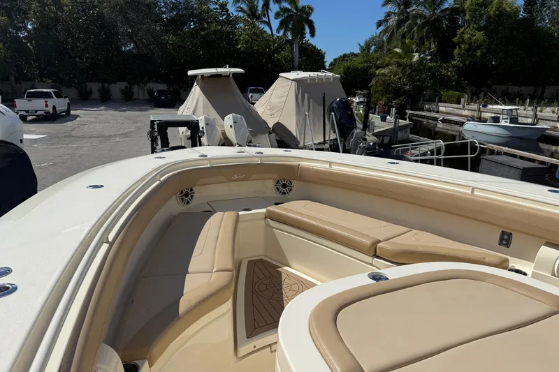 Slide: The Image of 2022 Scout 355 LXF boat interior with beige seating and docked boats in background. - 26