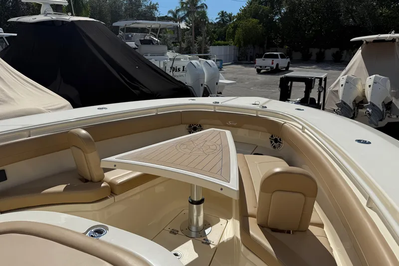Slide: The Image of 2022 Scout 355 LXF boat interior with tan seating and triangular table. - 28