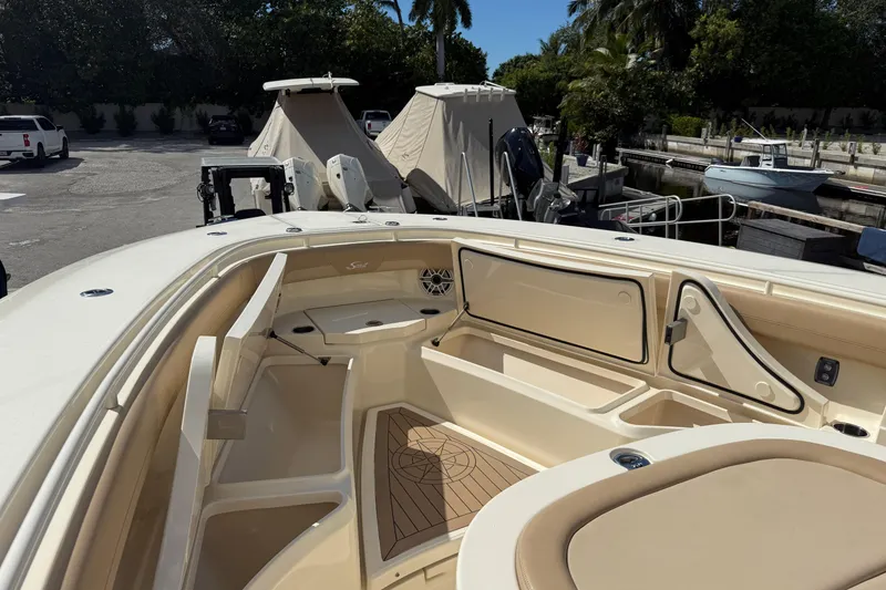 Slide: The Image of 2022 Scout 355 LXF boat interior with seating and storage, docked in a marina. - 31