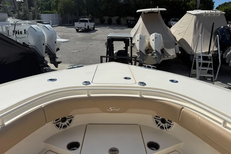 Slide: The Image of 2022 Scout 355 LXF boat interior with beige seating and docked boats in background. - 32